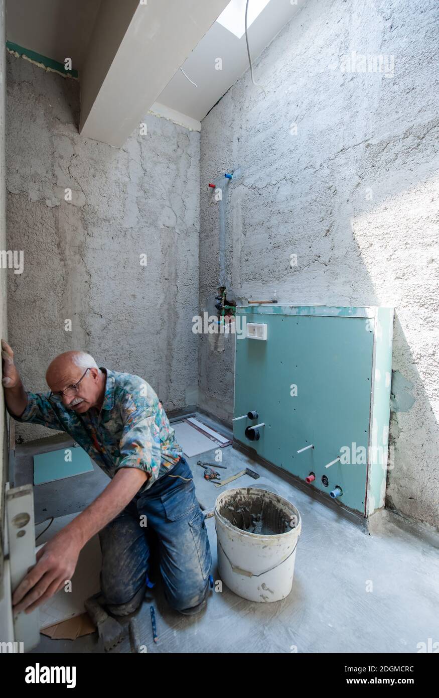 Worker using level tool while installing big ceramic tiles Stock Photo