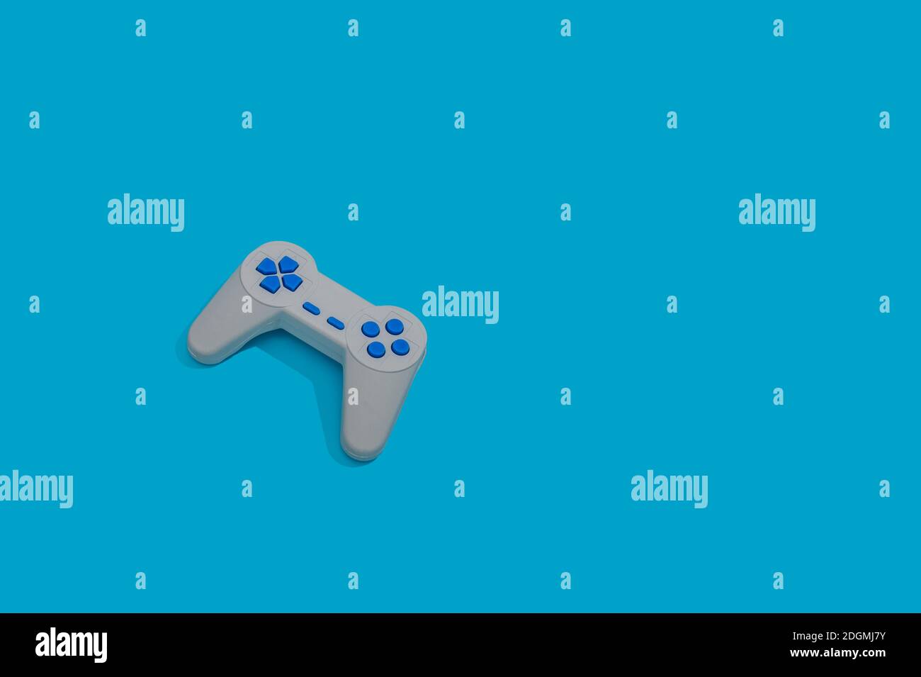 An old retro game joypad controller isolated on a pastel blue background Stock Photo