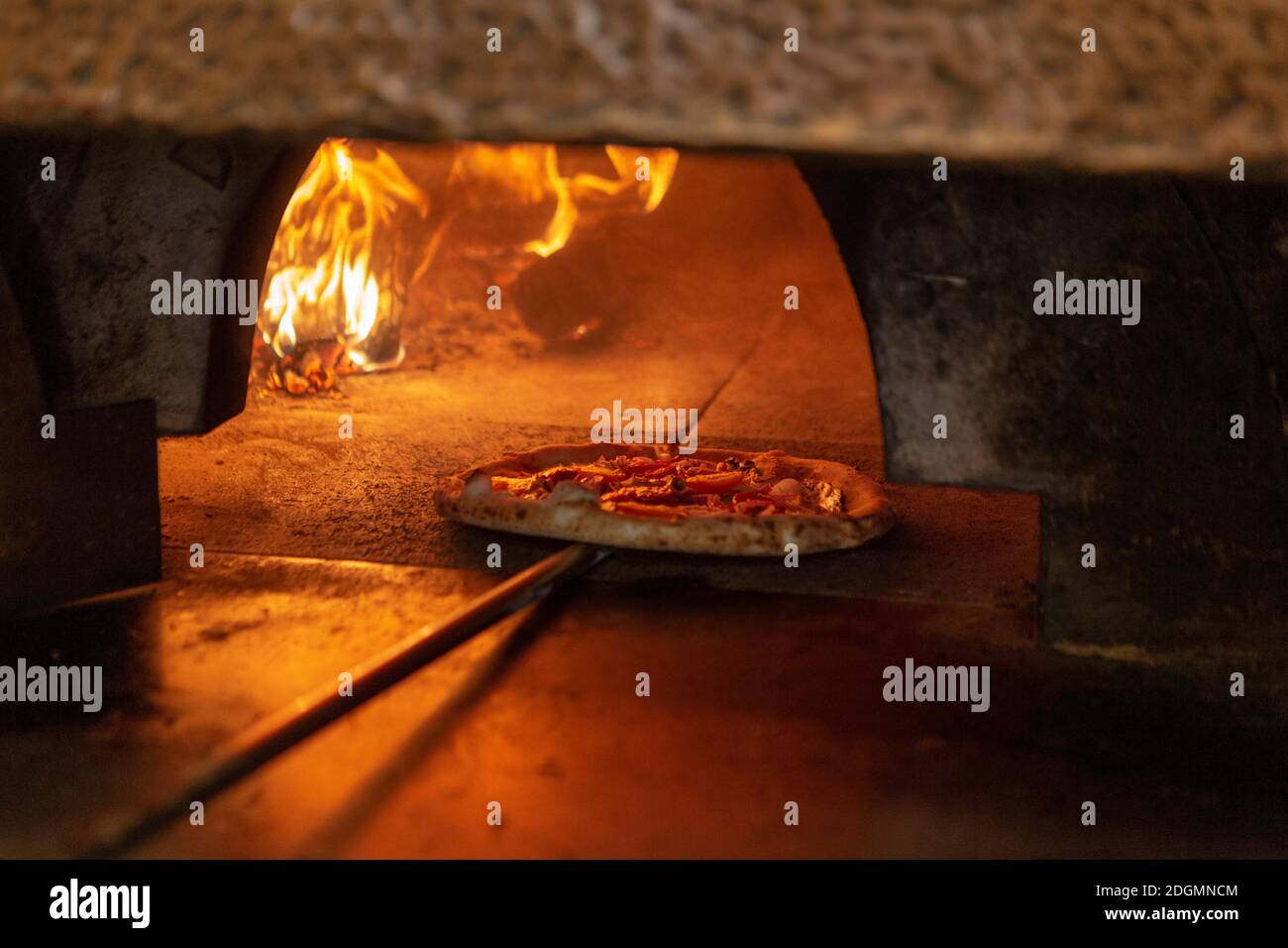 A pizza is placed into a wood burning oven in a restaurant in Rome Stock Photo