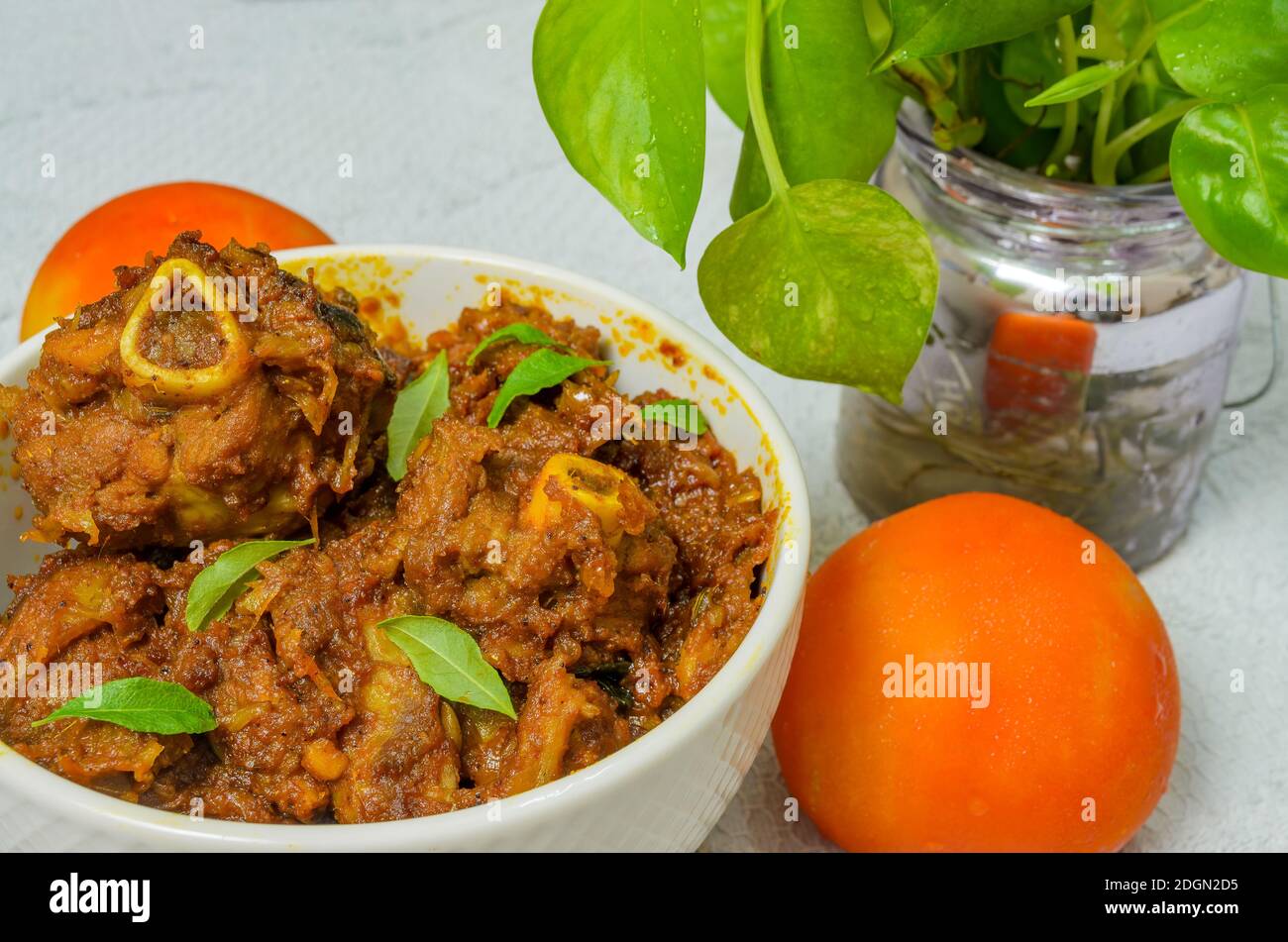 Yummy Mutton Roast in a white bowl along with a tomato. Stock Photo