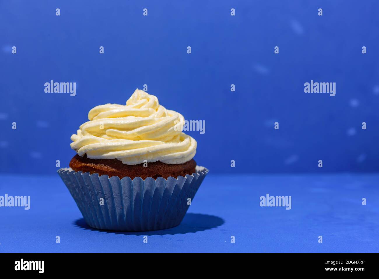 Cupcake on blue background with white buttercream frosting Stock Photo ...