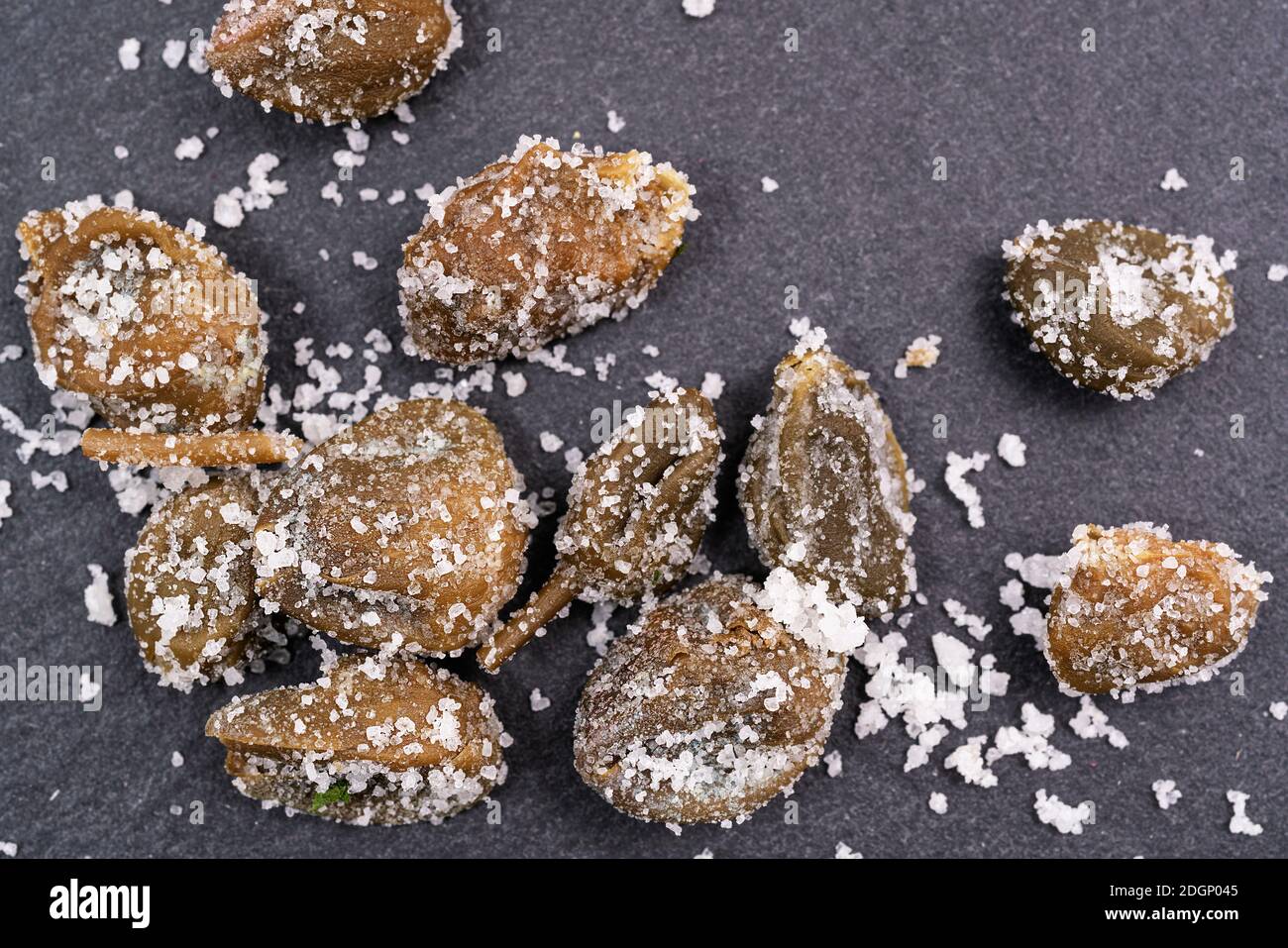some capers preserved in salt on a stone surface Stock Photo Alamy
