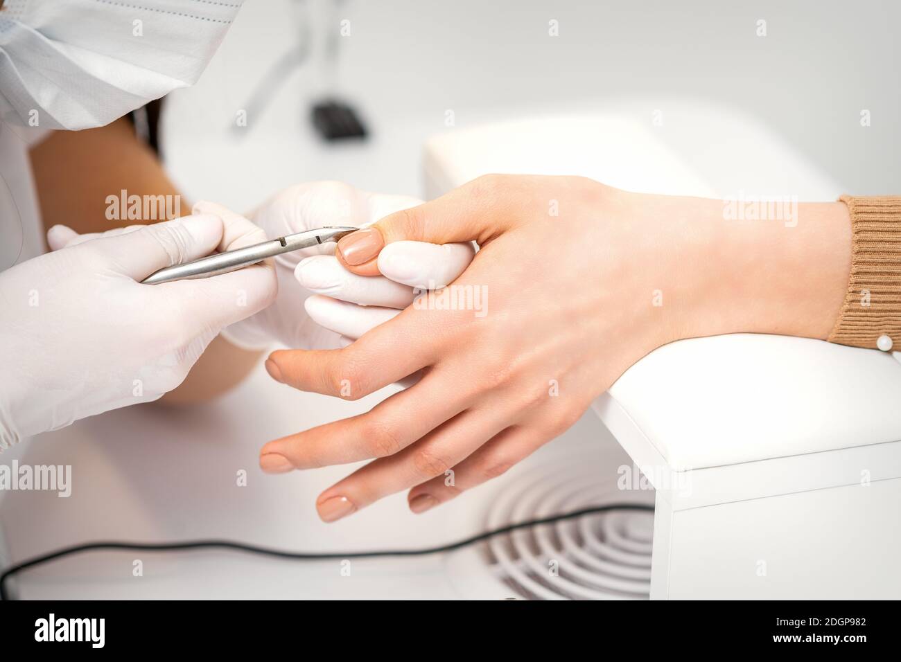 Manicure master is removing cuticles with a nail clipper in a nail