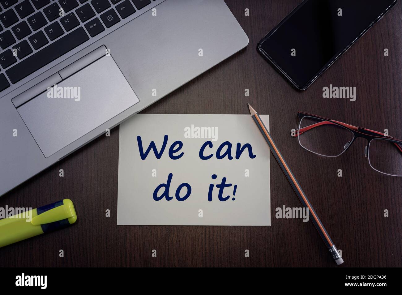 We can do it card. Top view of office table desktop background with laptop, phone, glasses and pencil with card with inscription we can do it.  Busine Stock Photo