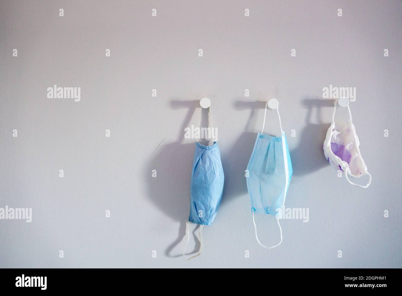 Three different sizes face mask hanging on a white wall Stock Photo