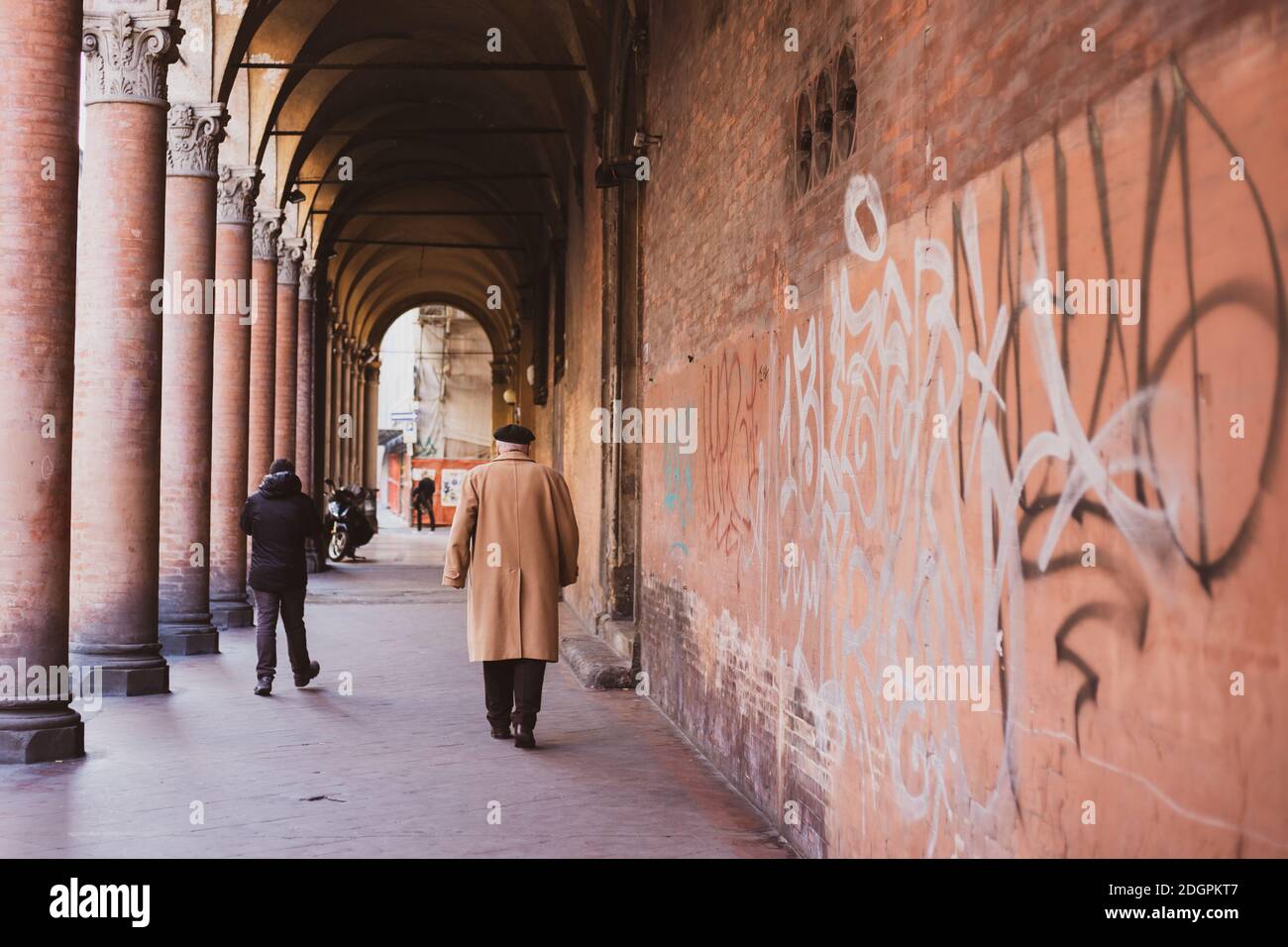 man walks under the arcades of Bologna Stock Photo