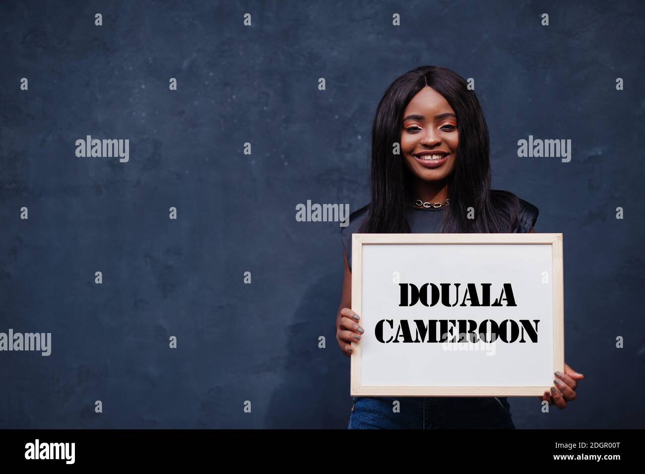 African woman hold white board with Douala Cameroon inscription. Most populous city in Africa concept. Stock Photo