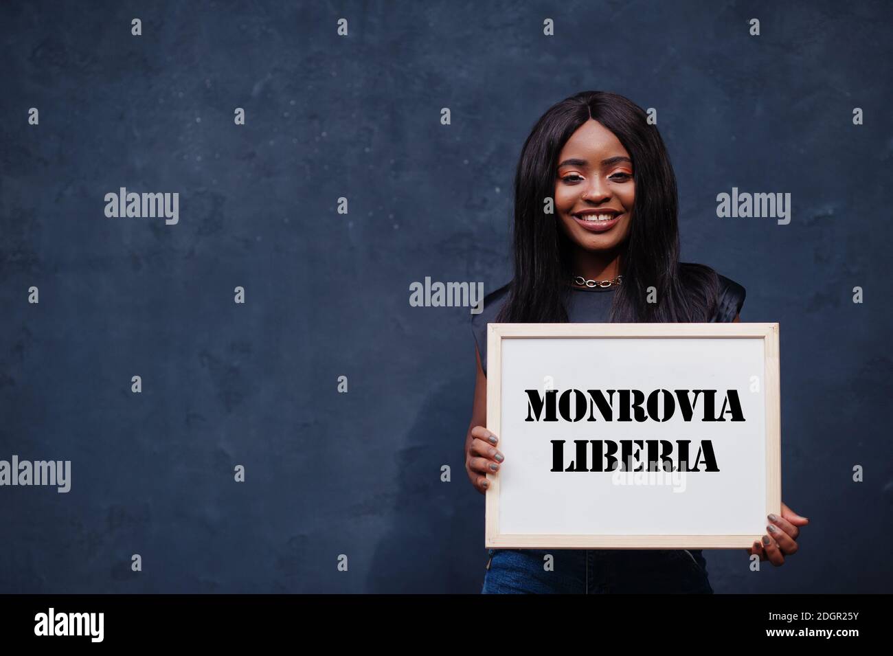 African woman hold white board with Monrovia Liberia inscription. Most populous city in Africa concept. Stock Photo