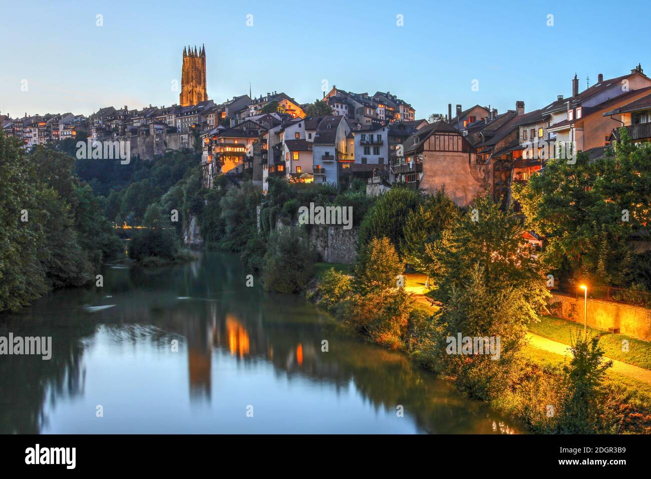 Fribourg, Switzerland as seen from the Pont de Millieu reflecting in the river Sarine at night with the tower of St. Nicholas cathedral overlooking th Stock Photo