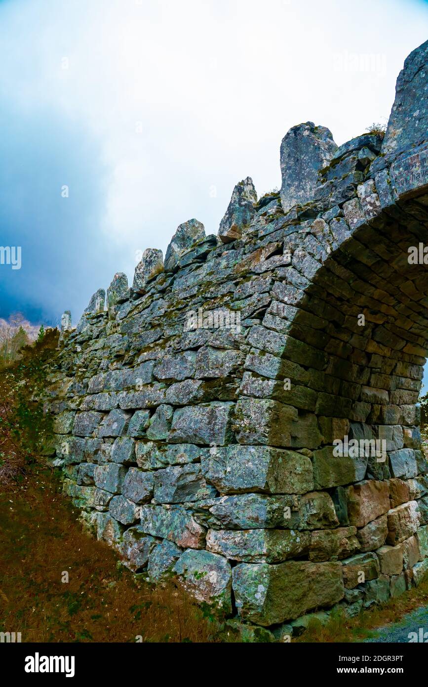 Old road bridge made from stone with an arch.  Stock Photo