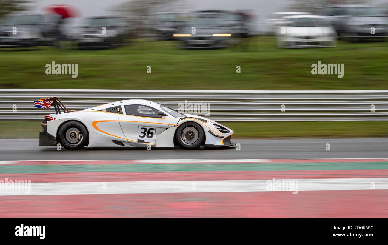 A panning shot of a racing car as it circuits a track. Stock Photo