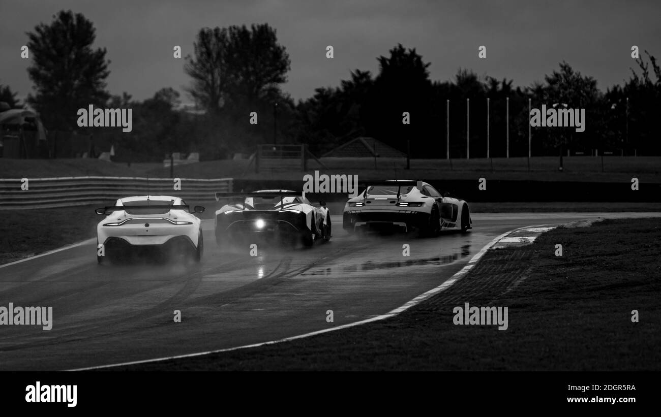 A shot of three racing cars as they circuit a track. Stock Photo