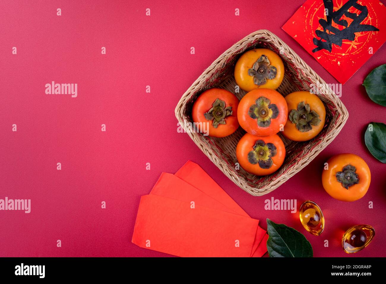 Top view of fresh sweet persimmons kaki with leaves on red table