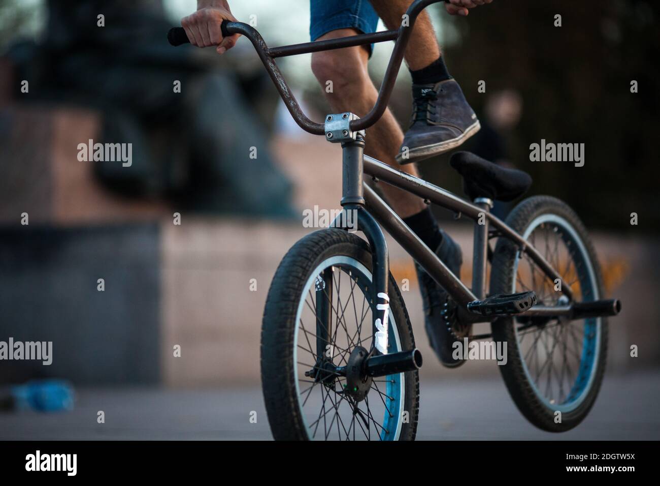 Young teenager bicyclist boy riding on beautiful orange bmx bicycle male hobby extreme sport male hobby lower part closeup backg Stock Photo