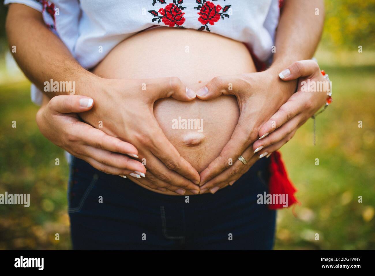Pregnant Belly with fingers Heart symbol. Beautiful Young Pregnant