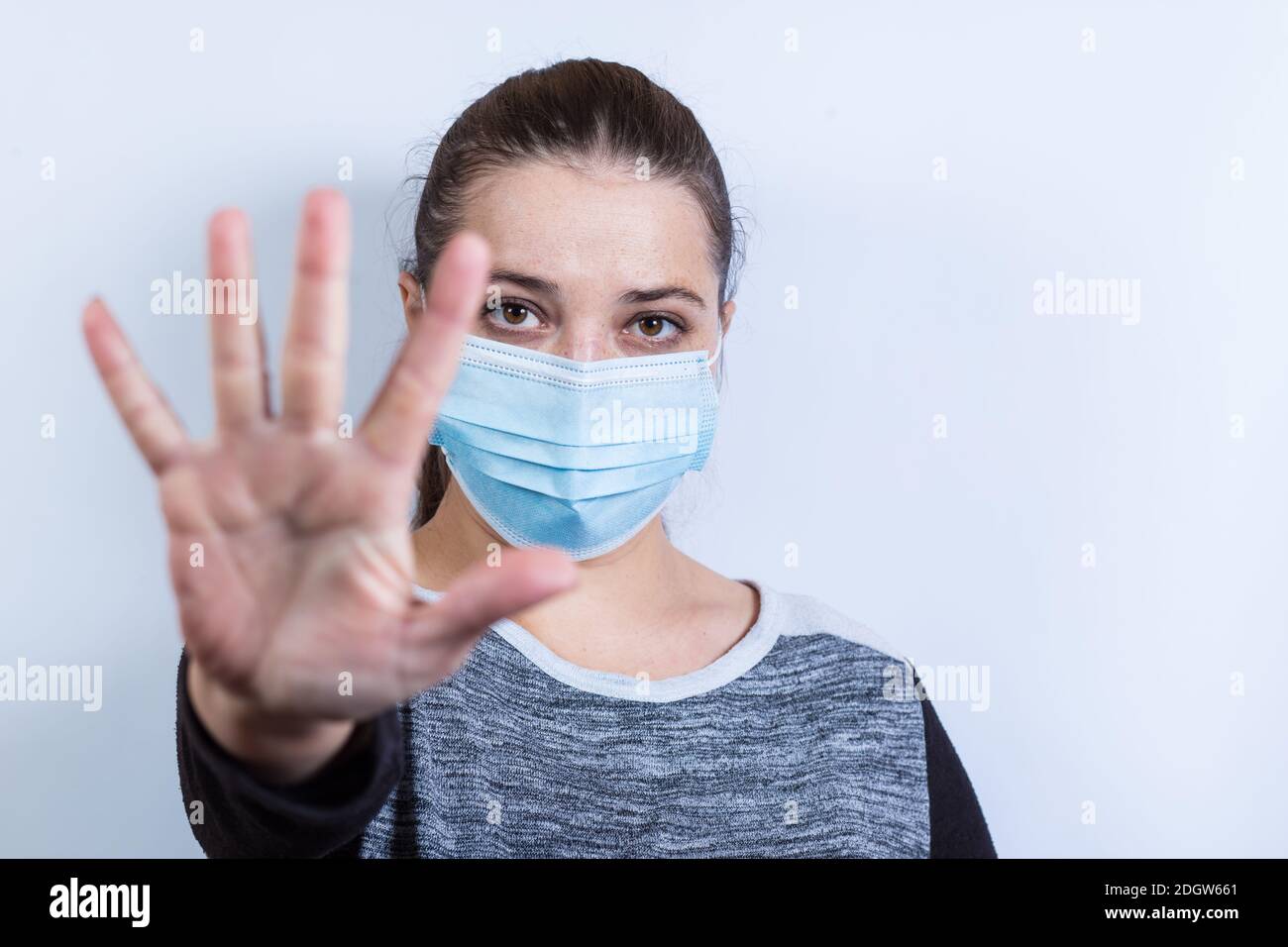Livestyle girl in mask shows stop with hand, to keep the distance. Stock Photo