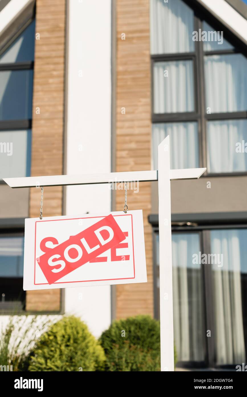 Sign with sold lettering with blurred front facade of modern house on ...