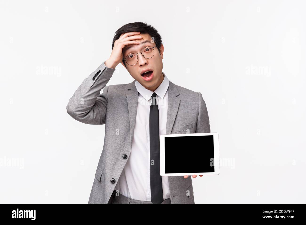 Waist-up portrait of shocked and astonished young asian man in suit realised something important, remember, touch forehead look Stock Photo