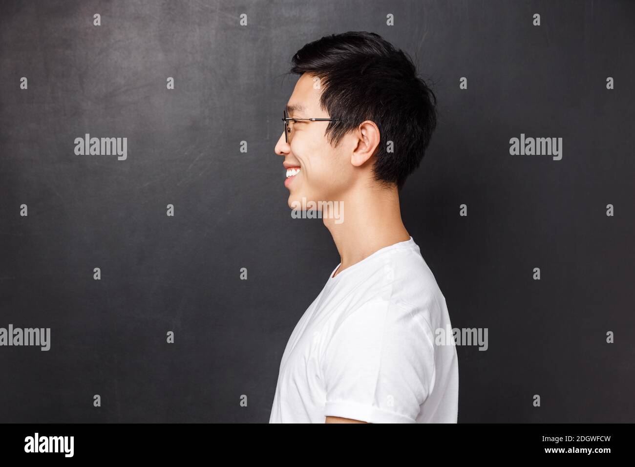 Profile portrait of happy smiling asian man in white t-shirt looking at left blank space, grinning friendly away as posing again Stock Photo