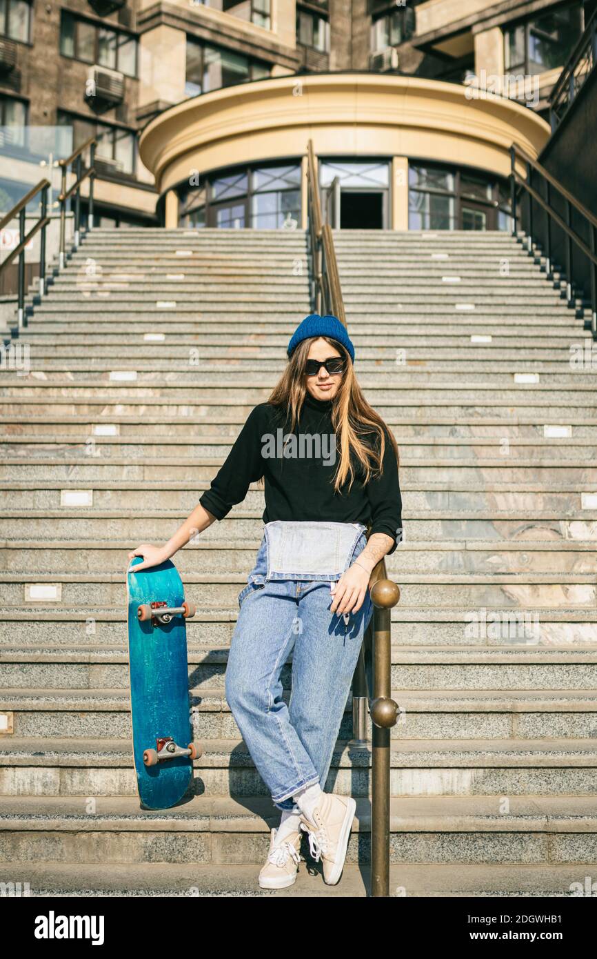 Stylishly dressed woman in blue denim jumpsuit posing with