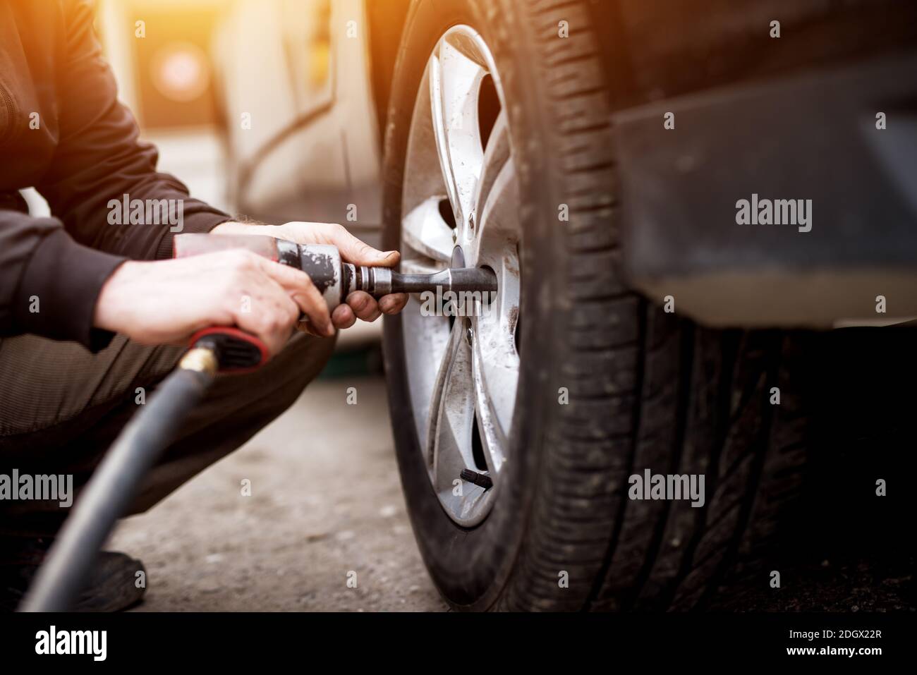 Выкаченное из гаража колесо. Шиномонтаж стоковые фото. Changing a Tire on an Electric car Wheel. Car Mechanic change Tires. Auto Mechanic with a Screwdriver.