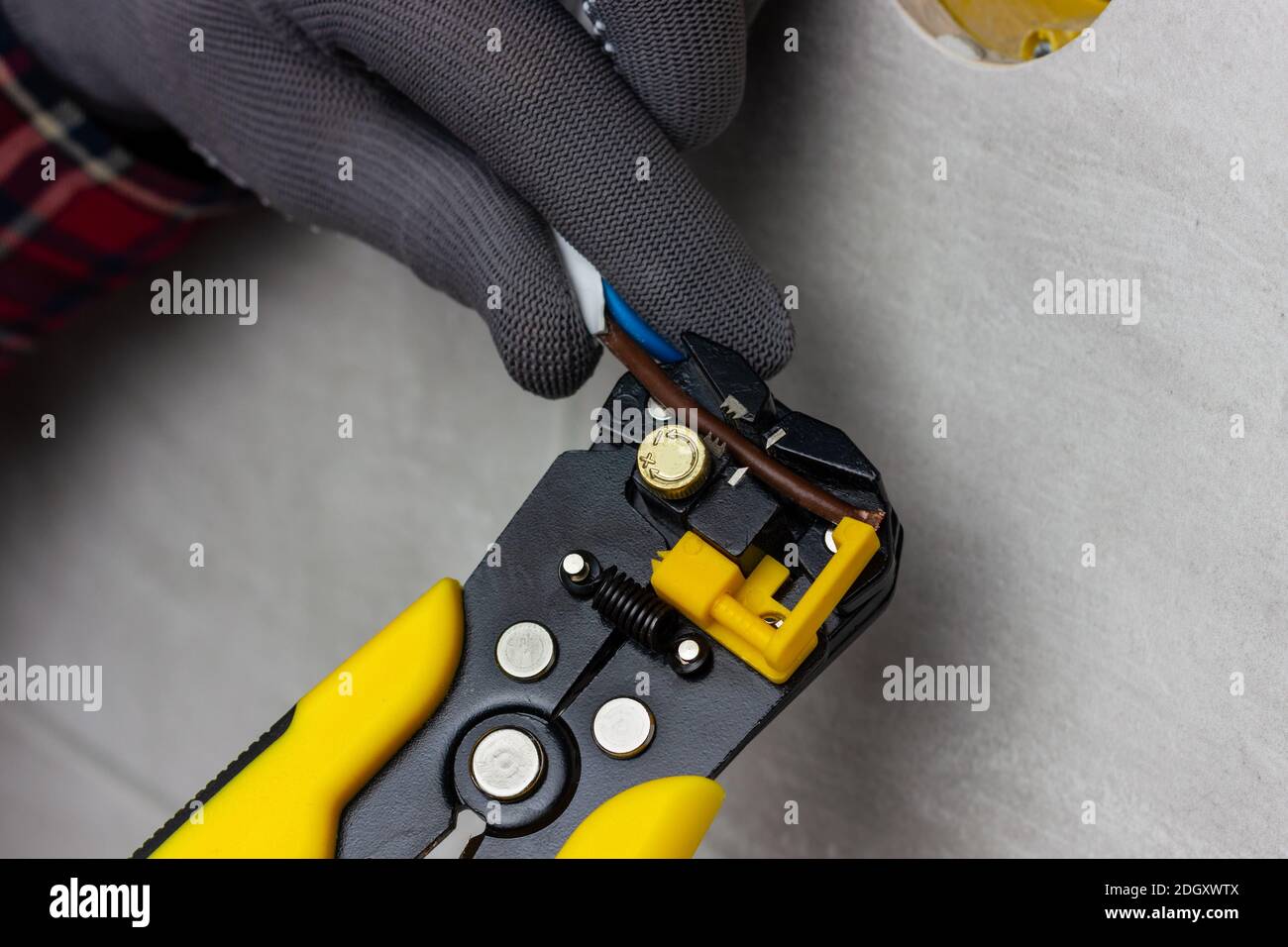 An electrician strips electrical wires. Yellow wire cutters strip the