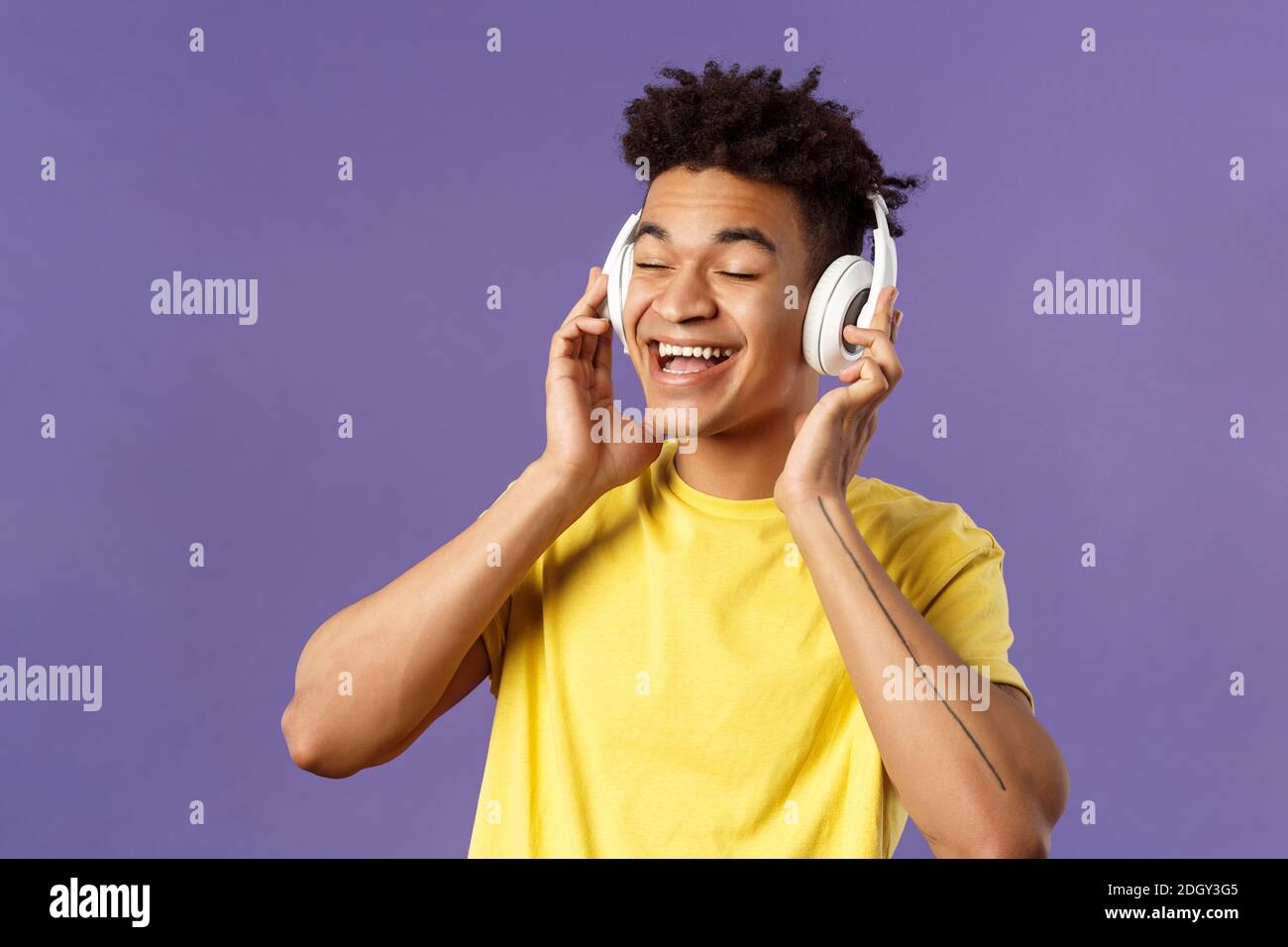 Close-up portrait of carefree, young upbeat man with dreads, close eyes and smiling pleased as listening to awesome new song fav Stock Photo