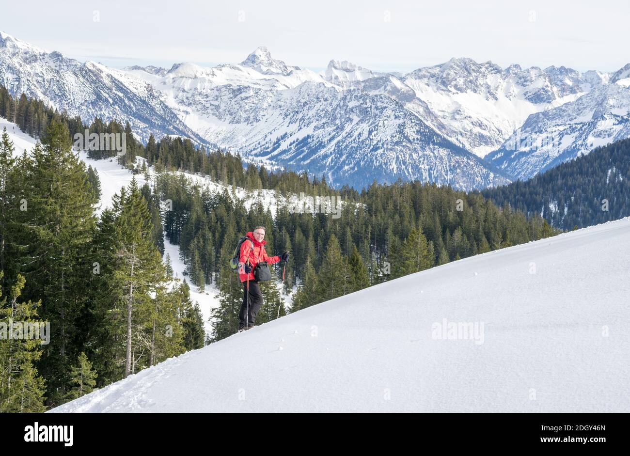 Senior man is snowshoe hiking in alpine snow winter mountains. Allgau, Bavaria, Germany. Stock Photo