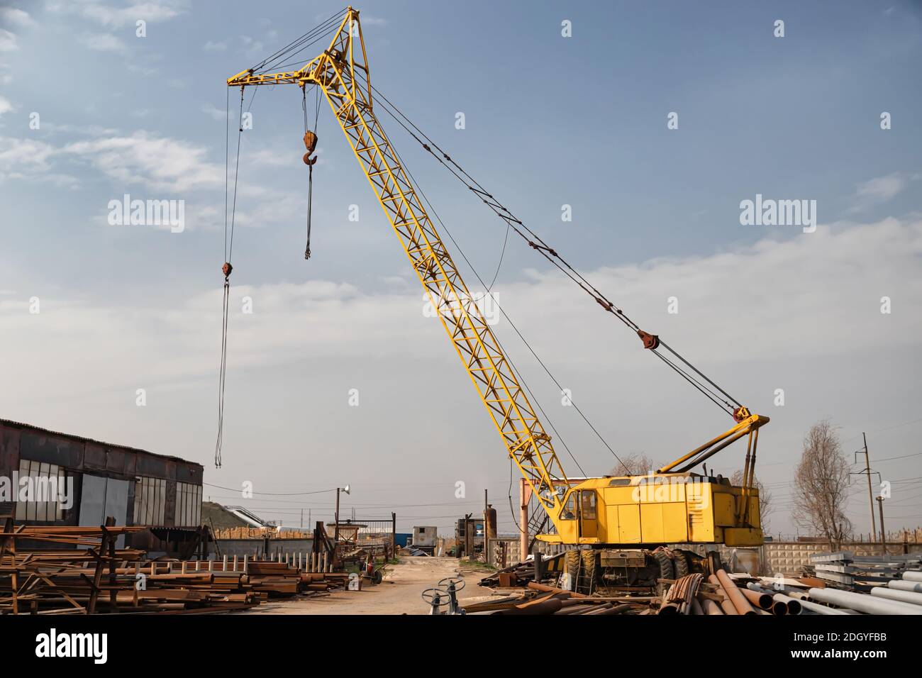 A large yellow crane stands on the basis of rolled metal Stock Photo