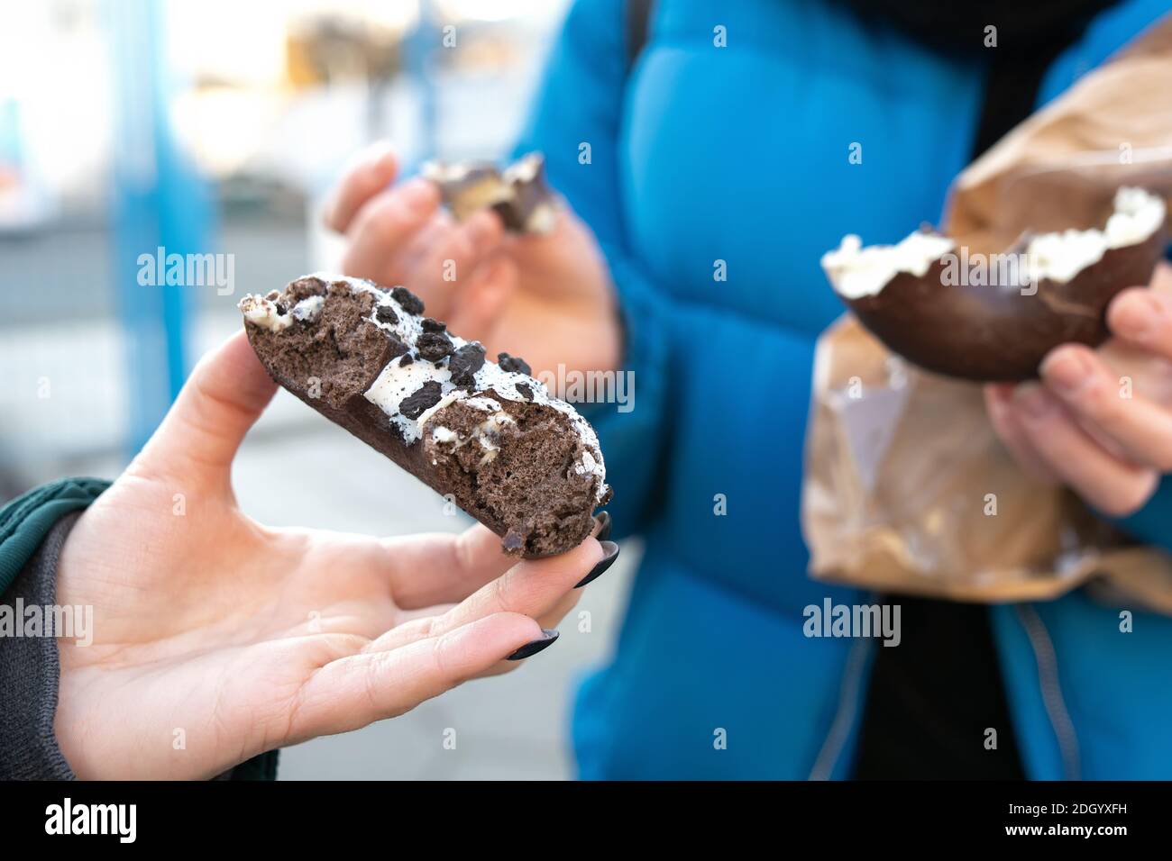 Female hands with tasty choco doughnut in the real life Stock Photo