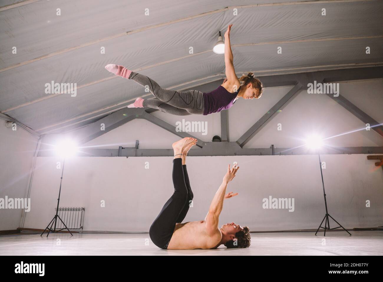 Couple doing acro yoga in a studio. Young people in yoga class in Throne  Pose. Yoga group concept Stock Photo - Alamy