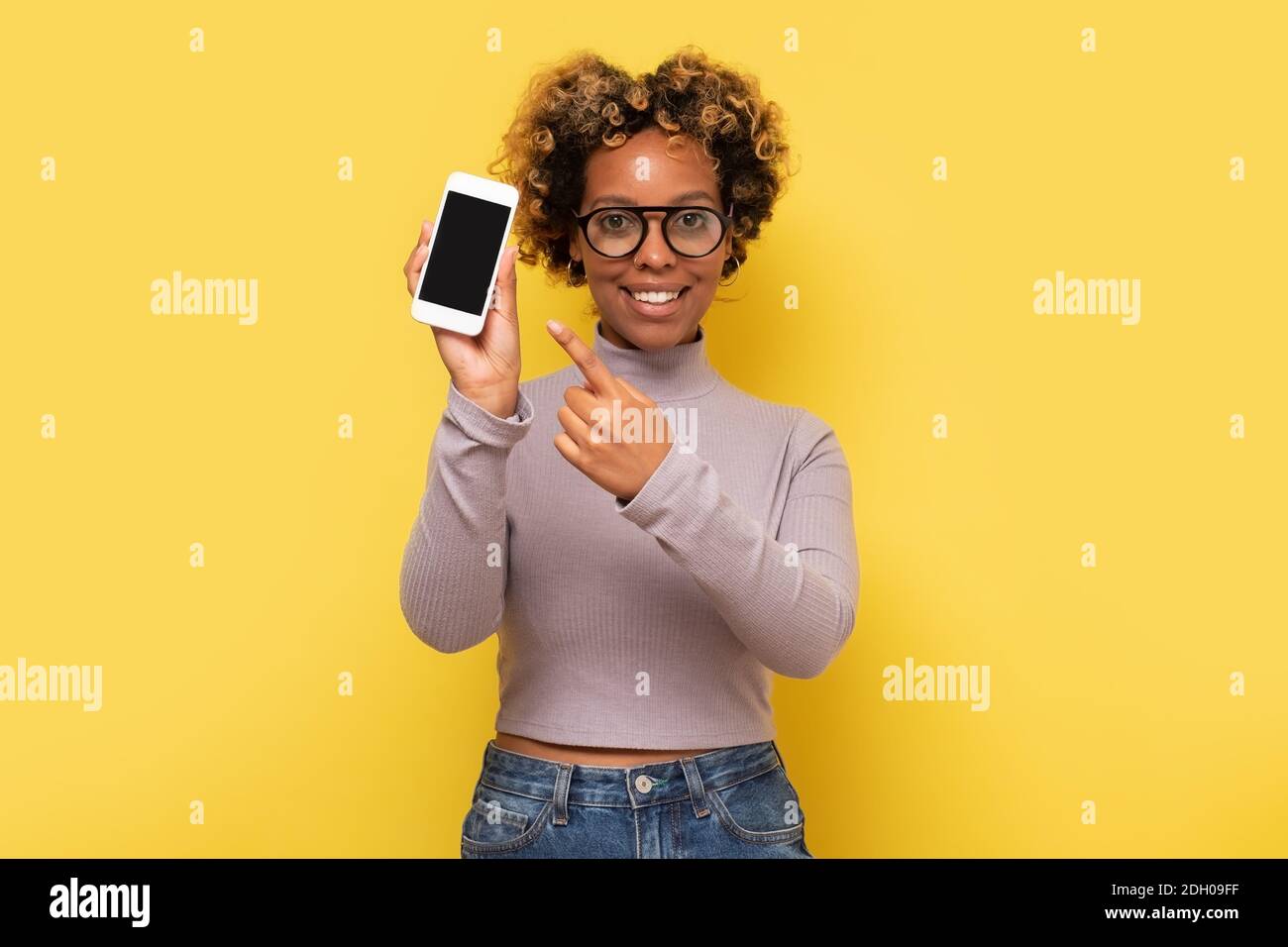 Excited african american woman pointing at smartphone with empty screen ...