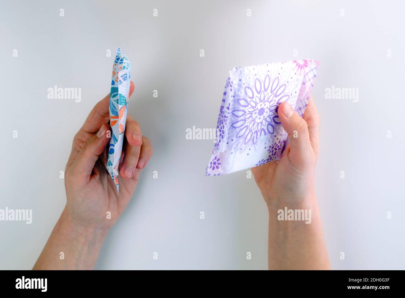 Hands displaying a choice between a tampon and a sanitary towel as a period product Stock Photo