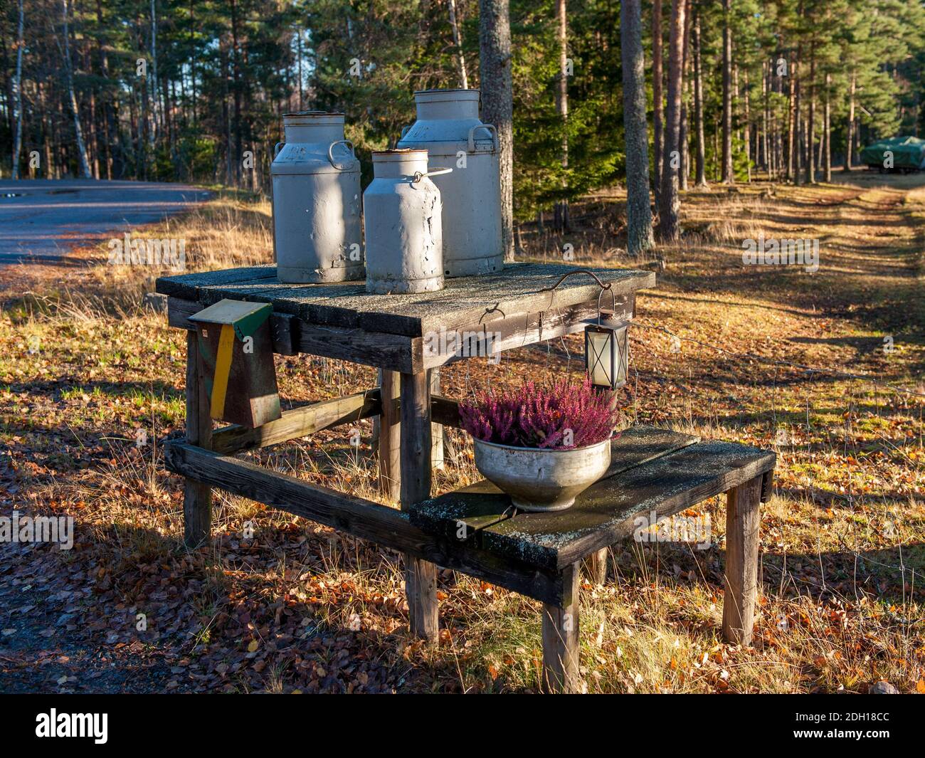 Traditional milk churn stand maintained for decorative purposes along a country road in county Ostergotland of Sweden Stock Photo