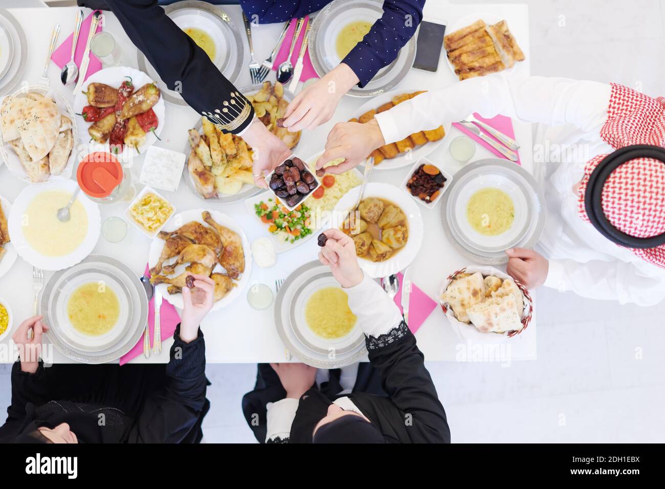 Muslim family having Iftar dinner eating dates to break feast top view Stock Photo