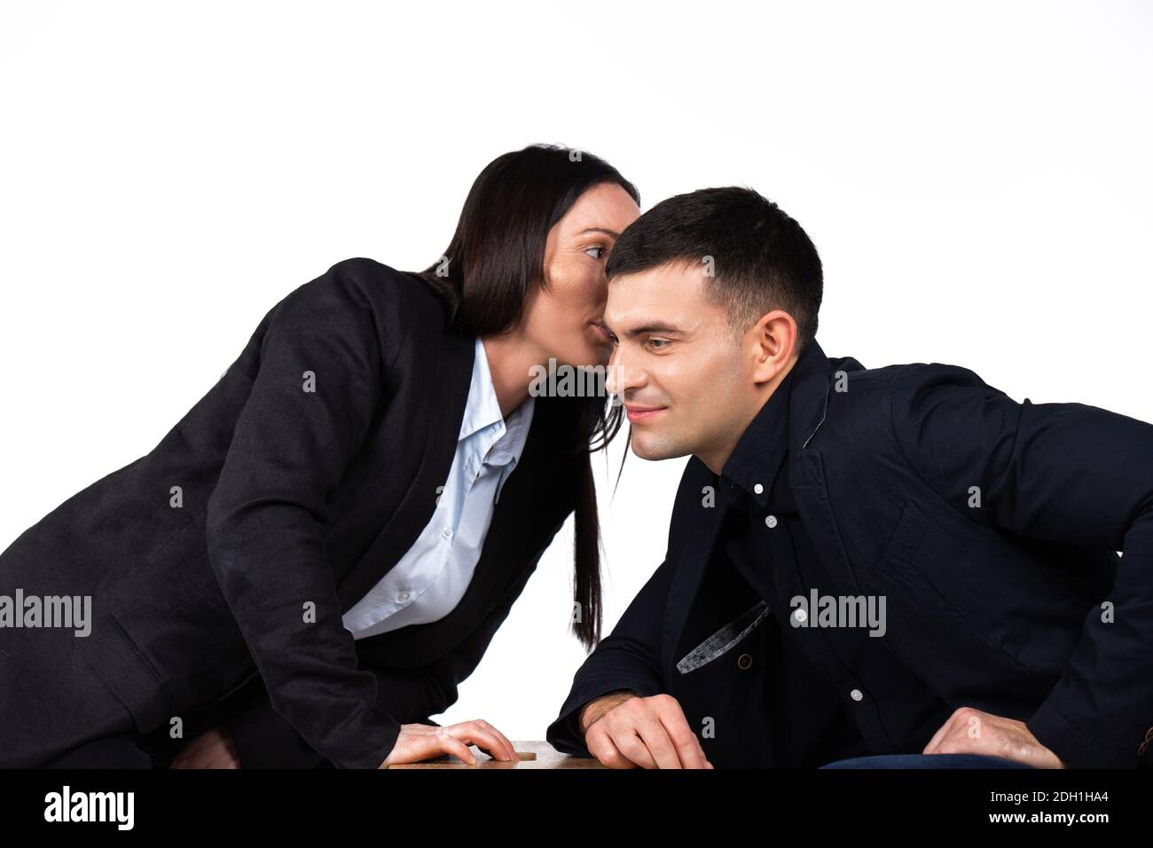 Battle between business partners. Businesswoman whispers something in the ear of businessmen. White background. Stock Photo