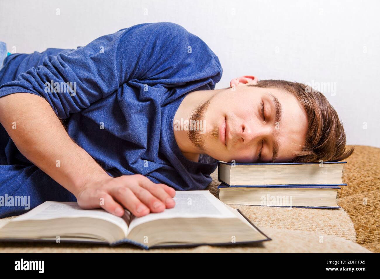 Tired Young Man sleep on the Sofa with the Books Stock Photo