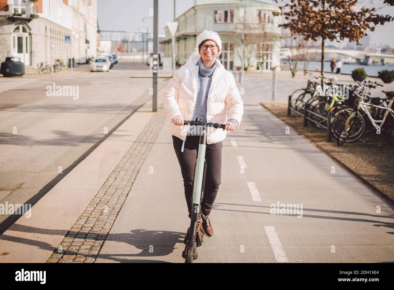 Young woman riding an electric scooter on bike path in copenhagen