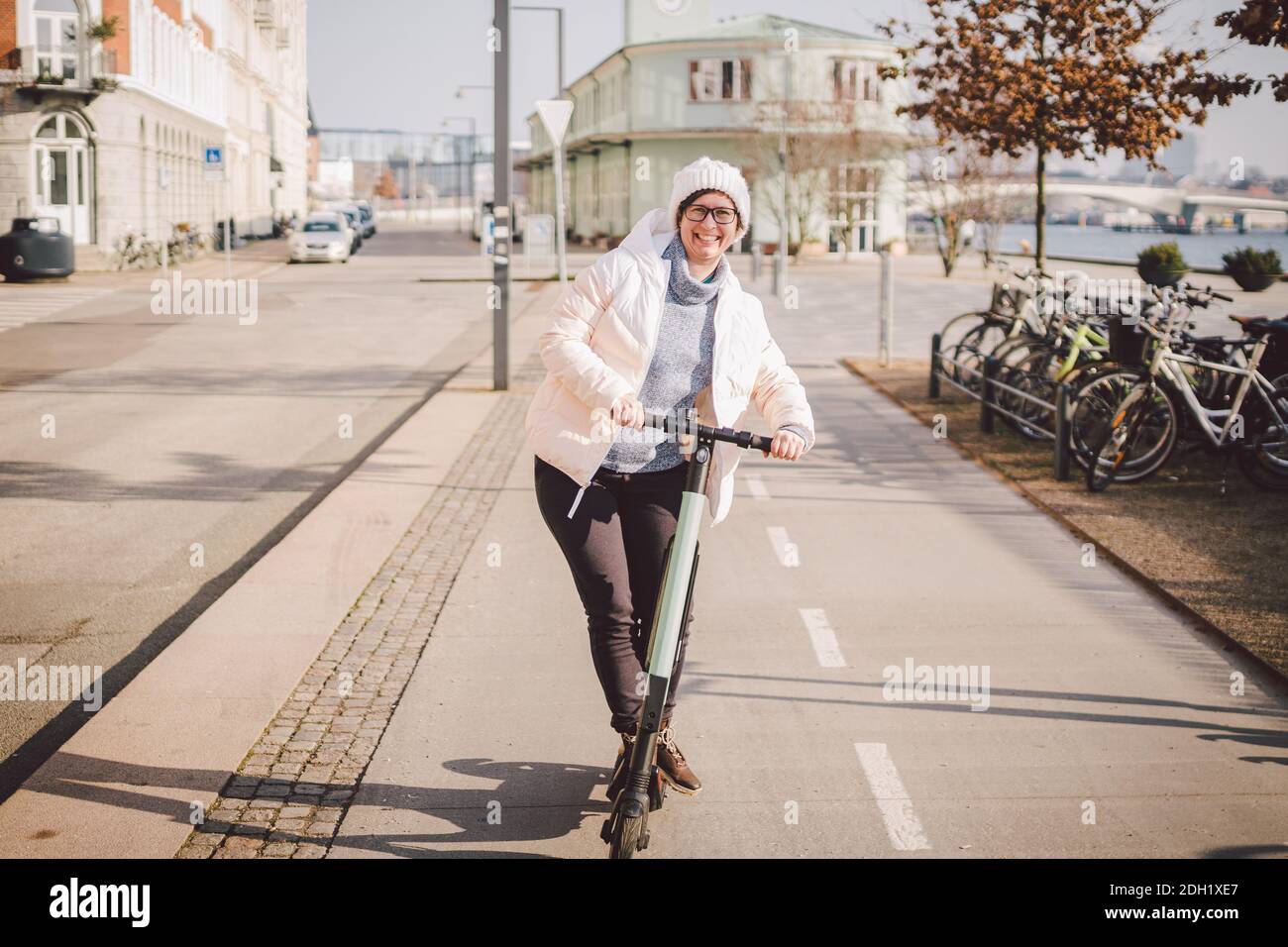 Tourist woman rent Electric scooter in danish capital Copenhagen. Female holding steering column knob with electric kick scooter Stock Photo