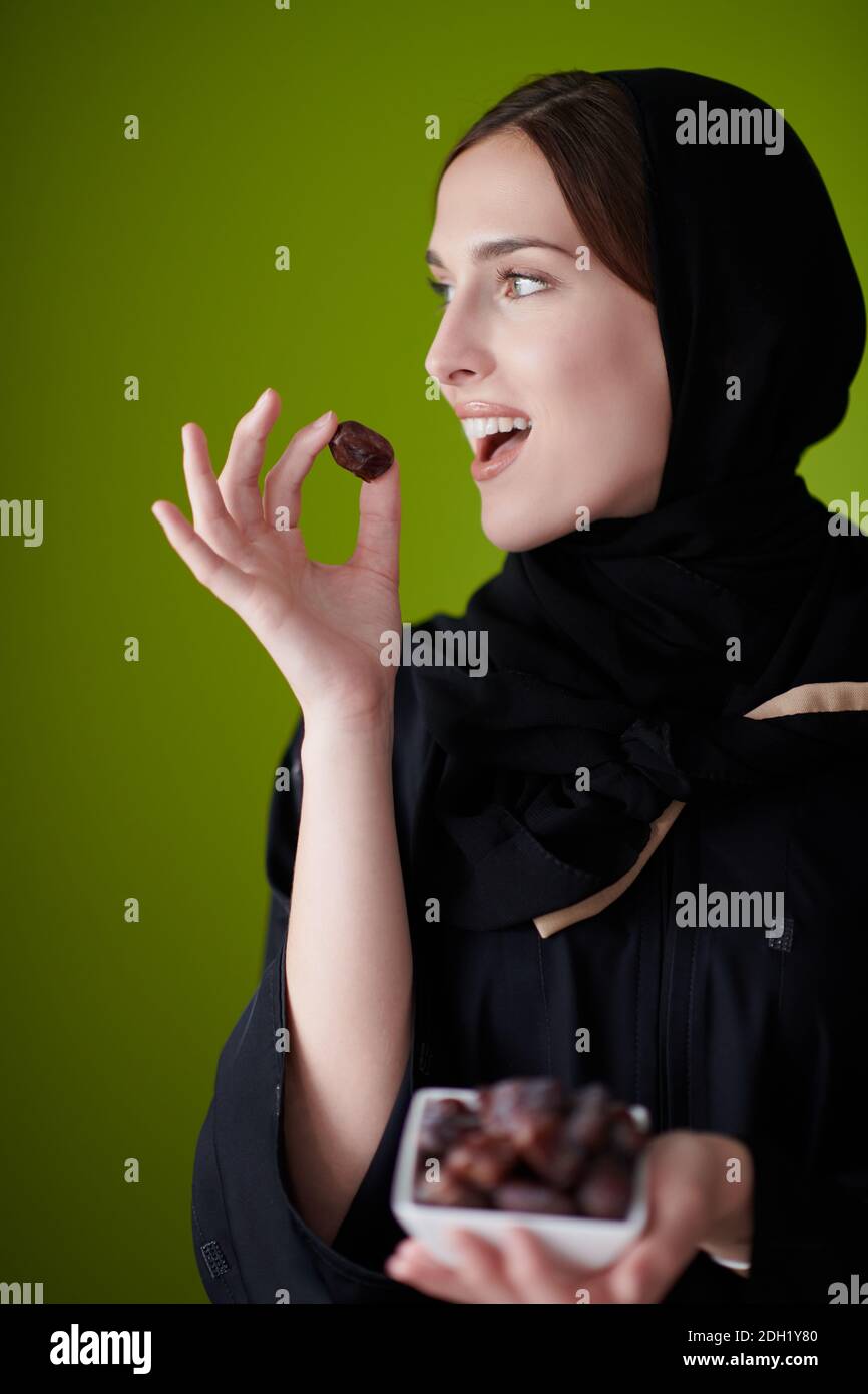 Woman in Abaya Holding a Date Fruit and glass of water Stock Photo