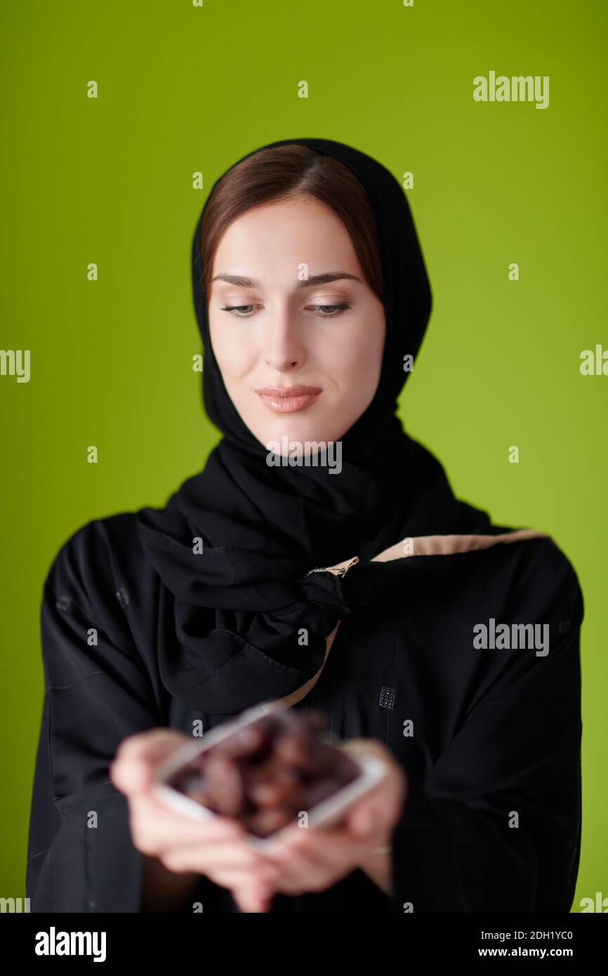 Woman in Abaya Holding a Date Fruit and glass of water Stock Photo