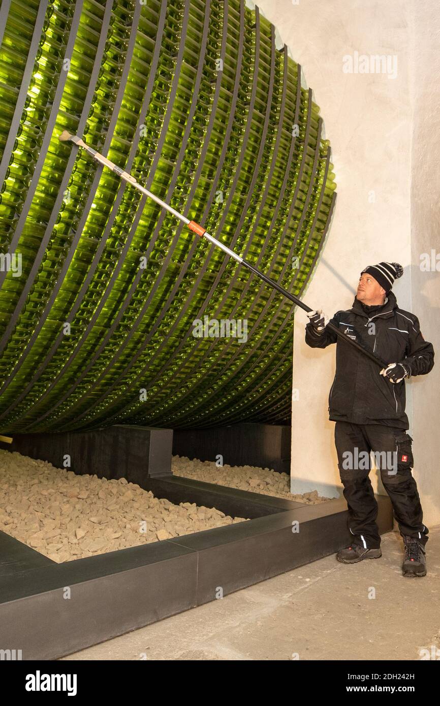 04 December 2020, Saxony, Königstein: Jens Hickmann cleans with a brush and an extension from the outside over the wine bottles. More than 11,000 bottles are assembled in a huge bottle barrel in the giant wine barrel cellar of Magdalenenburg. The bottle barrel is a multimedia artistic installation and symbolises the storage of wine barrels at the time of August the Strong. Photo: Daniel Schäfer/dpa-Zentralbild/ZB Stock Photo