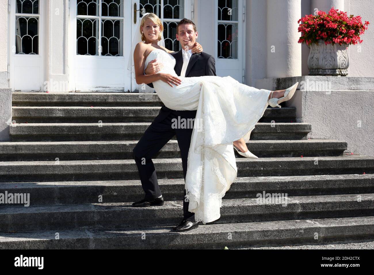 Brautpaar, Bräutigam trägt Braut auf dem Arm eine Treppe hinunter, MR: Yes Stock Photo