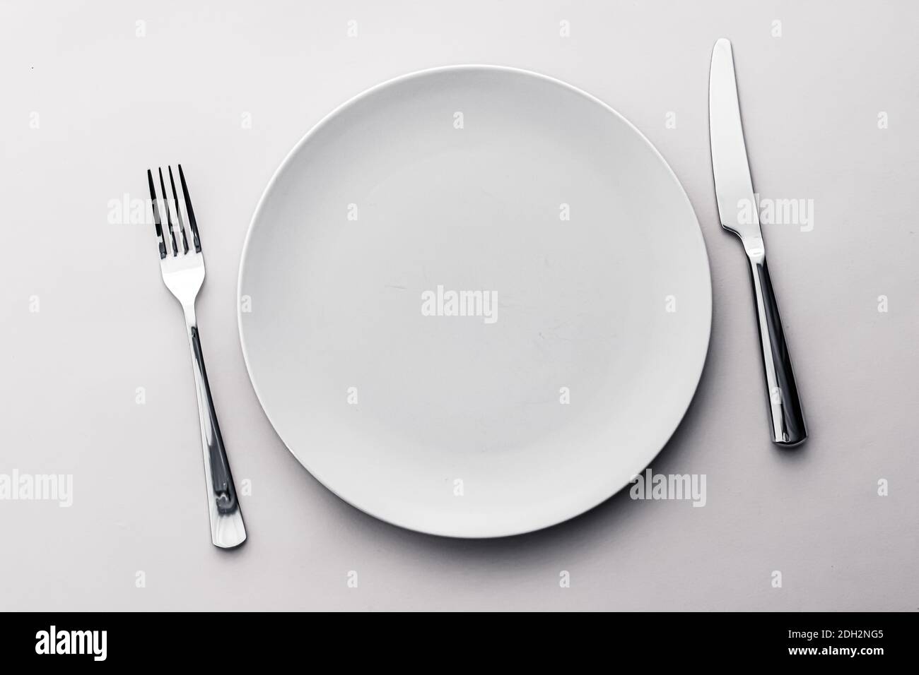 Empty plate and cutlery as mockup set on white background, top ...