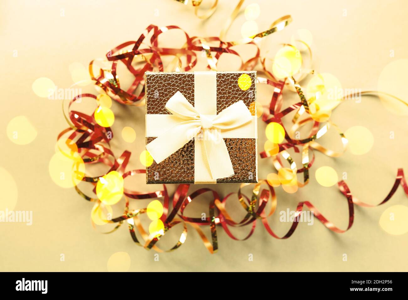 Christmas gift box with festive ribbons, golden stars and blurred