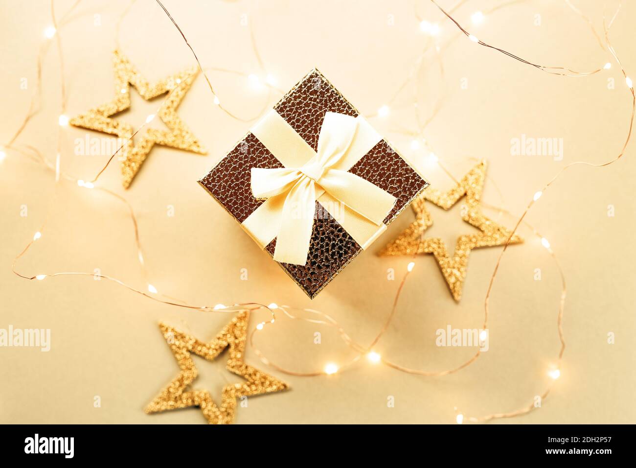 Christmas gift box with festive ribbons, golden stars and blurred