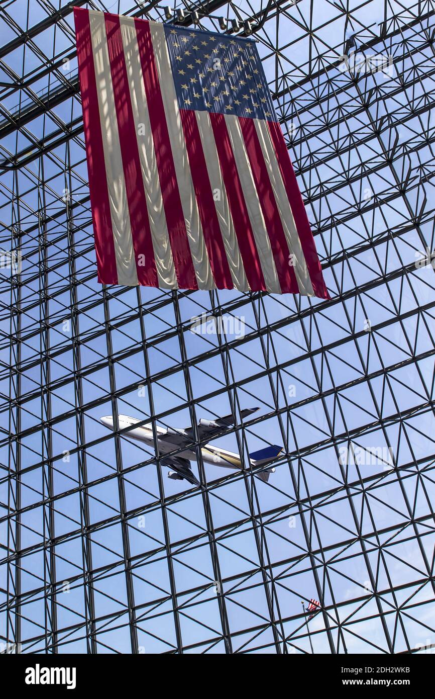 A Commercial Aircraft Takes Off With An American Flag In The Foreground Stock Photo