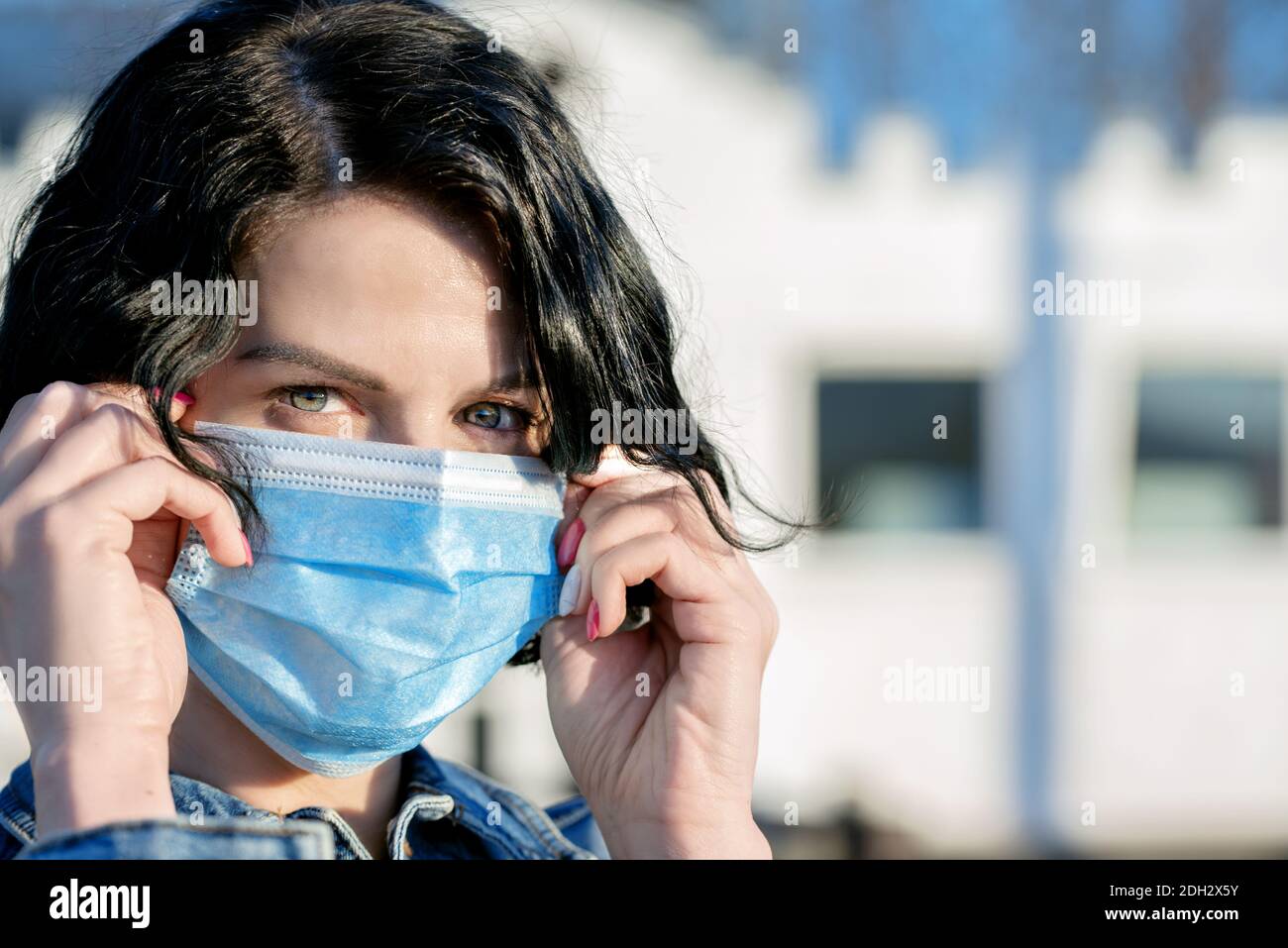 Portrait of woman on the street wearing protective mask as protection against infectious diseases, flu or covid Stock Photo