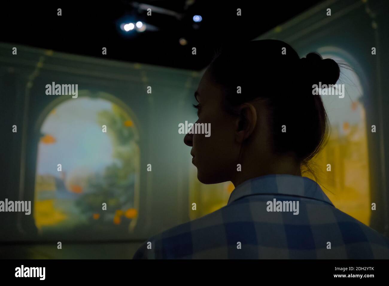 Young woman looking around at immersive exhibition - video art installation Stock Photo
