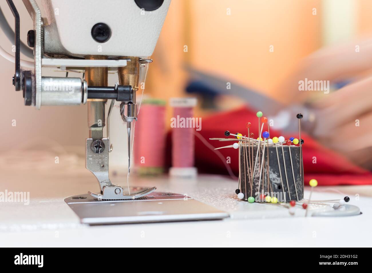 A needle and thread sew up a hole in a denim. Work of a seamstress or  tailor with a needle Stock Photo - Alamy